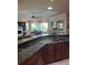 Open concept kitchen features granite counters, dark wood cabinets, and opens into living room at 1802 Hartford Path, The Villages, FL 32162