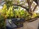 Inviting outdoor patio with comfortable seating, lush landscaping, and shade provided by a mature tree at 1802 Hartford Path, The Villages, FL 32162