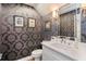 Elegant powder room features patterned wallpaper, stylish lighting, and a sleek white vanity for a sophisticated look at 1831 Mizell Ave, Winter Park, FL 32789