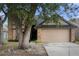Two story tan house with a two-car garage, with a large tree in the front yard at 2239 Meadowmouse St, Orlando, FL 32837