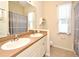 Well-lit bathroom featuring a double sink vanity with a tan countertop and a window with sheer curtains at 2503 Squaw Crk, Clermont, FL 34711