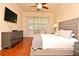 Comfortable main bedroom with hardwood floors, ceiling fan, TV, and stylish gray furniture at 2503 Squaw Crk, Clermont, FL 34711