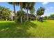 Expansive backyard featuring lush green grass, mature palms, a screened-in pool, and a playset at 383 Brushwood Ln, Winter Springs, FL 32708