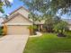 Charming two-story home with a lush green lawn, mature trees, and a two-car garage at 383 Brushwood Ln, Winter Springs, FL 32708