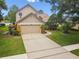 Tan two-story home with a spacious driveway, a two car garage, and a well-maintained lawn at 383 Brushwood Ln, Winter Springs, FL 32708