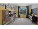Study room with two wooden desks, chairs, a black cabinet with shelves, and yellow accent wall near a bright window at 3908 Diving Dove Ln, Bartow, FL 33830
