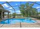 Beautiful in-ground pool features a lake view, screened enclosure, and mature trees at 5108 Sailwind Cir, Orlando, FL 32810
