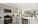 Modern kitchen with stainless steel appliances, gray cabinets, and an open layout into the dining and living spaces at 5113 Forget Me Not Ave, Lake Hamilton, FL 33851