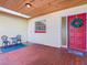 Charming front porch with red-tiled floor, front door with wreath, and cozy seating area under wood ceiling at 601 Francis St, Kissimmee, FL 34741