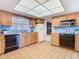 Traditional kitchen featuring wooden cabinets, black appliances, tile flooring, and a unique grid-patterned ceiling light at 601 Francis St, Kissimmee, FL 34741