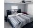 Bedroom showcasing a modern ceiling fan, a bed with striped bedding, and a sunny window with privacy blinds at 6216 Beaumont Ave, Orlando, FL 32808