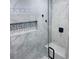 Modern shower featuring grey tiles, a built-in shelf, and a comfortable bench seat at 6216 Beaumont Ave, Orlando, FL 32808