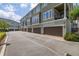 View of townhouse exteriors and garages with tree landscaping, and brick paver driveway at 704 Grado Pt, Oviedo, FL 32765
