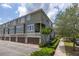 Exterior view of a multi-story townhouse with a two-car garage and a well-manicured lawn, and large windows at 704 Grado Pt, Oviedo, FL 32765
