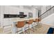 Modern kitchen boasts white cabinets, stainless steel appliances, a black tile backsplash, and a breakfast bar with four leather chairs at 704 Grado Pt, Oviedo, FL 32765