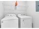 Functional laundry room with white washer and dryer, and overhead storage shelf at 7565 Laureate Blvd # 3408, Orlando, FL 32827