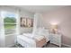 Cozy bedroom featuring a white metal bed frame, canopy, view to the lake and soft pink accent wall at 8391 Madrid St, Lakeland, FL 33810