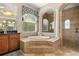 Bright bathroom featuring a soaking tub with tile surround, a vanity and a glass enclosed shower at 9032 Tavolini Ter, Windermere, FL 34786