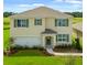 Charming two-story home with a manicured lawn, attached garage, and welcoming entryway at 947 Princess Sabal Pt, Haines City, FL 33844