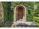Charming stone archway entrance with a rustic wooden door and lush greenery, creating an inviting curb appeal at 996 Fairview Ave, Mount Dora, FL 32757