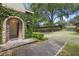 Stunning stone archway entrance with lush greenery and brick driveway, offering a grand welcome to this luxurious home at 996 Fairview Ave, Mount Dora, FL 32757