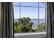 Serene water view from a large picture window, framed by elegant curtains and lush greenery at 996 Fairview Ave, Mount Dora, FL 32757