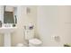 Well-lit half bathroom with pedestal sink, toilet, and decorative accents, conveniently located near the staircase at 10940 Leafshore Loop, Orlando, FL 32829