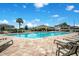 Community pool with lounge chairs on a brick patio, palm trees, clear blue water, and neighborhood homes at 10940 Leafshore Loop, Orlando, FL 32829
