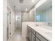 Modern bathroom featuring double sinks, grey cabinets, and a glass-enclosed shower for a spa-like experience at 11607 Sunsail Ave, Orlando, FL 32832