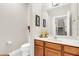 Bathroom with a wooden vanity, white countertop, and large mirror, complemented by neutral walls and modern fixtures at 1545 Caterpillar St, St Cloud, FL 34771