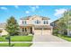 Two-story beige home showcasing well-maintained landscaping, a two-car garage, and traditional design at 1545 Caterpillar St, St Cloud, FL 34771
