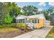 Inviting yellow home with white trim, well-maintained yard, and a private driveway leading to a detached garage at 1624 Park Lake St, Orlando, FL 32803