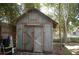Backyard shed featuring double doors and a decorative sign, enclosed by a wooden fence and lush trees at 1644 Cypress Woods Cir, St Cloud, FL 34772