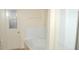 Bright bathroom features tile floors, a white tiled tub surround, and linen storage beside a window door at 1644 Cypress Woods Cir, St Cloud, FL 34772