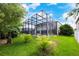 Backyard featuring a manicured lawn, tropical plants, and a screened-in pool at 16500 Cedar Run Dr, Orlando, FL 32828