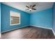 An empty blue bedroom with wood-look flooring and a ceiling fan at 16500 Cedar Run Dr, Orlando, FL 32828