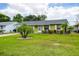 Attractive single-story home featuring a green lawn, landscaped with a palm tree and charming shutters on the windows at 206 Montana Ave, St Cloud, FL 34769