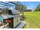 Outdoor patio featuring a stainless steel Weber grill and screened enclosure surrounded by a green lawn at 2624 Daulby St, Kissimmee, FL 34747