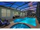A sparkling blue swimming pool and hot tub, framed by a screened enclosure, lounge chairs, and outdoor dining at 2624 Daulby St, Kissimmee, FL 34747