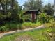 Overgrown exterior of a single-story home featuring a red painted exterior and lush green foliage at 2638 S Laurel Ave, Sanford, FL 32773