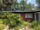 Exterior side view of red brick home with satellite dish and multiple windows amidst dense foliage at 2638 S Laurel Ave, Sanford, FL 32773