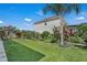 Landscaped backyard features a lush lawn, mature trees, and well-maintained garden beds, with beautiful flowers at 3966 Steer Beach Pl, Kissimmee, FL 34746