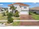 Elegant two-story home featuring a terracotta roof, lush landscaping, and a brick driveway leading to a two-car garage at 3966 Steer Beach Pl, Kissimmee, FL 34746