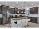 Modern kitchen with stainless steel appliances, dark cabinets, granite countertops, a kitchen island with seating and pendant lights at 3966 Steer Beach Pl, Kissimmee, FL 34746
