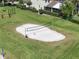 Aerial view of a community volleyball court featuring a sand pit and net surrounded by lush green grass at 3966 Steer Beach Pl, Kissimmee, FL 34746