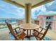 Balcony with wooden table and chairs overlooking colorful buildings and clear blue skies at 5 Riverwalk Dr # 601, New Smyrna Beach, FL 32169