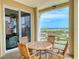 Balcony with table and chairs overlooking the water and lush landscape with colorful buildings in the distance at 5 Riverwalk Dr # 601, New Smyrna Beach, FL 32169