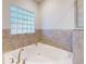 Bathroom with a corner soaking tub, tiled surround, and blue glass block window at 5 Riverwalk Dr # 601, New Smyrna Beach, FL 32169