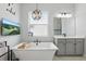 Close up of soaking tub and vanity in bright bathroom featuring stylish light fixture and TV at 5427 Orange Orchard Dr, Winter Garden, FL 34787