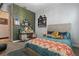 Cozy bedroom with decorative wallpaper, desk with mirror, shelves, and a comfy bed with vibrant pillows and patterned blanket at 5427 Orange Orchard Dr, Winter Garden, FL 34787
